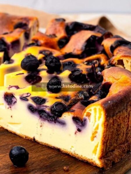 Preheat oven to 325°F (160°C). Line an 8-inch springform pan with parchment paper. Mix cream cheese and sweetener on medium speed until smooth and creamy (2–3 minutes). Add eggs one at a time, mixing on low speed until fully incorporated. Blend in protein powder and vanilla until smooth. The batter should be thick but pourable. Gently fold in blueberries using a spatula. Pour into prepared pan and smooth the top. Bake for 35–40 minutes until edges are set and center slightly jiggles. Cool at room temperature 30 minutes, then refrigerate at least 2 hours before slicing.